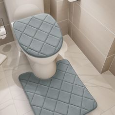 a toilet seat cover and rug in a bathroom with beige tile walls, white flooring and gray tiles on the wall