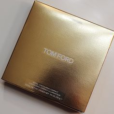 the box is gold and has a logo on it that says tom ford in white letters