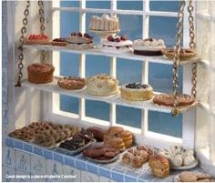 an assortment of cakes and pastries are displayed on a window sill in front of a blue tiled wall