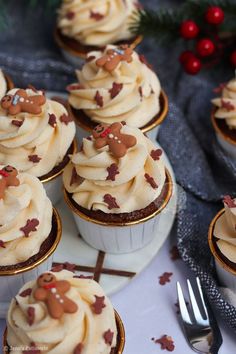 cupcakes with frosting and reindeer decorations are on a plate next to silverware