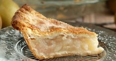 a piece of pie sitting on top of a glass plate next to two pears