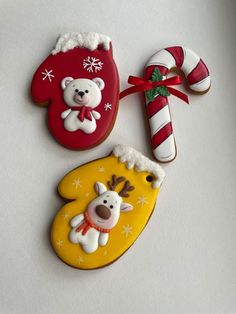 three decorated cookies are sitting on a white surface next to candy canes and an ornament