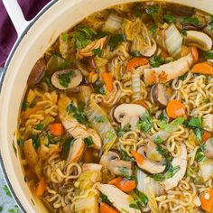 a pot filled with noodles and vegetables on top of a purple cloth next to chopsticks