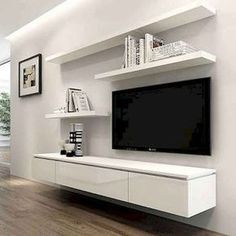 a living room with white furniture and a flat screen tv mounted on the wall above it