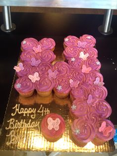 cupcakes with pink frosting are arranged in the shape of flowers and butterflies