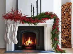 a fireplace decorated for christmas with stockings and holly wreaths on it's mantle