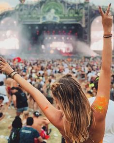 a woman with her arms in the air at a music festival