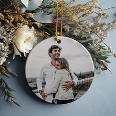 an ornament with a photo of a man and woman on it next to flowers