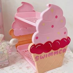 a pink ice cream sundae sitting on top of a table next to a teddy bear