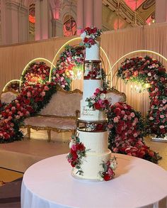 a three tiered wedding cake sitting on top of a table with flowers around it