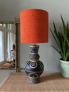 a black and white vase sitting on top of a table next to a potted plant