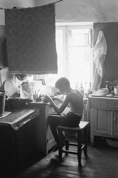 a woman sitting in a chair at a kitchen counter working on a paper workbook