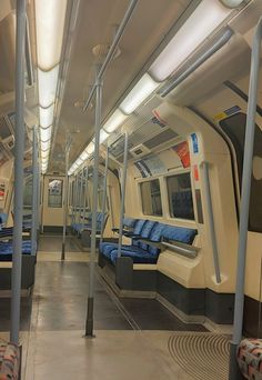 an empty train car with blue seats and metal poles on the ceiling, along with no people