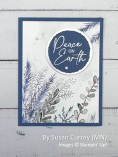 a card with the words peace on earth written in blue and white ink, surrounded by evergreen leaves