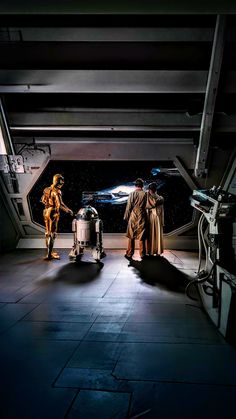 two people standing in front of a star wars scene with lights on and droid next to them