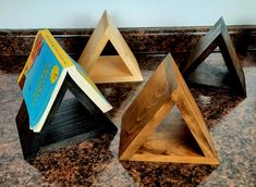 three wooden bookshelves sitting on top of a marble counter next to each other