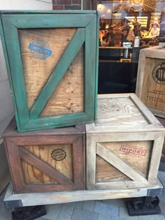 three wooden crates stacked on top of each other in front of a storefront window