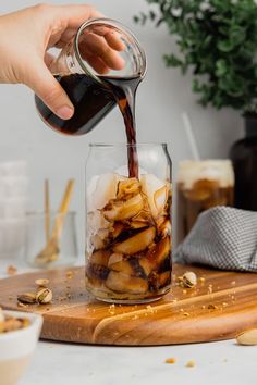 someone pouring syrup into a glass filled with food