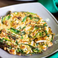 a white plate topped with an omelet covered in cheese and veggies