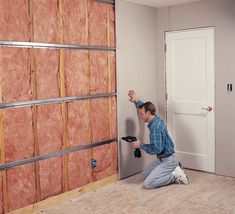 a man kneeling down in front of a wall that is being built with plywood