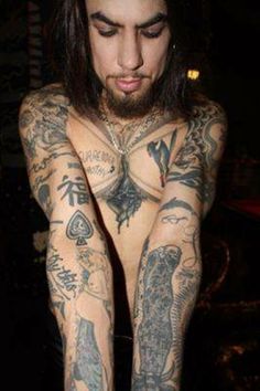 a man with long hair and tattoos on his body is posing in front of the camera