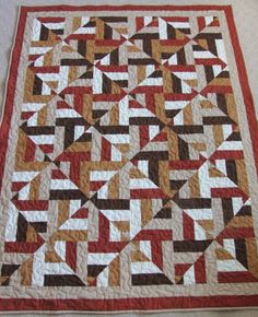 a quilted table topper is shown in red, brown and white colors with an abstract design