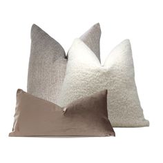 three pillows in various colors and sizes on a white background, one is light brown the other is dark gray