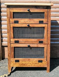 a wooden cabinet with two drawers and wire on the bottom, next to a log wall