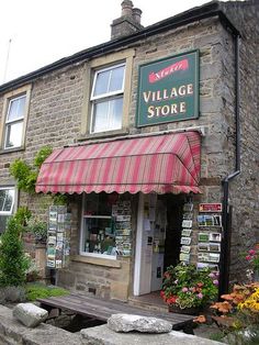 the village store is located in an old stone building with red and white awnings