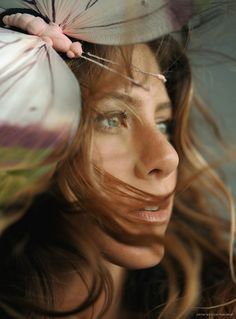 a woman with long hair holding an umbrella over her head and looking at the camera