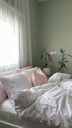 an unmade bed with white sheets and pink pillows in front of a large window