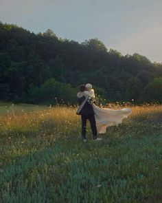 a man and woman are standing in the grass with their arms wrapped around each other