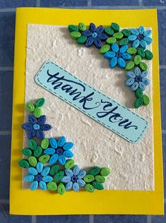 a thank you card with blue flowers and green leaves on yellow paper that says thank you