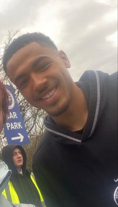 a man and woman standing next to each other in front of a blue sign that says park