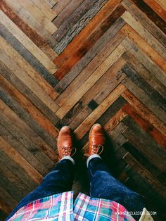 a person wearing brown shoes standing in front of a wooden floor with multicolored herringbones