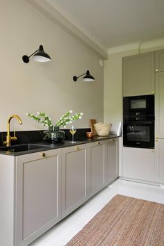 a kitchen with white cabinets and gold faucets on the counter top, along with black appliances