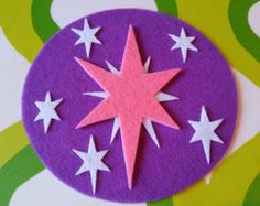 a purple and white circular with stars cut out of it sitting on a colorful surface