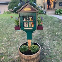 a wooden barrel filled with flowers and books in front of a house on the grass