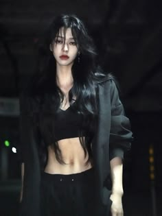 a woman with long black hair walking down a runway