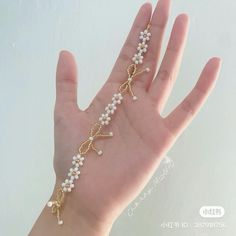 a person's hand wearing a gold bracelet with white pearls and cross charms on it