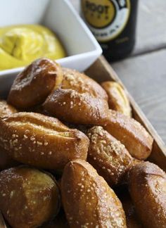 a wooden box filled with doughnuts next to a bottle of beer