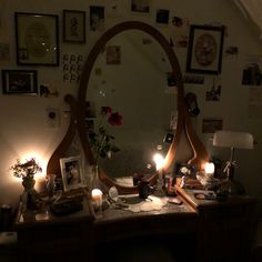 a desk with a mirror, candles and pictures on the wall