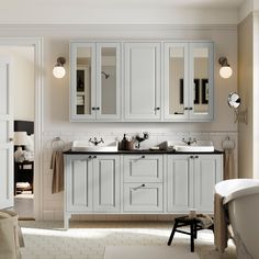 a white bathroom with two sinks, mirrors and bathtub in the middle of it