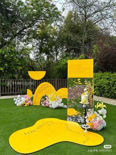 yellow and white flowers are on display in the grass near a sign that says, happy birthday