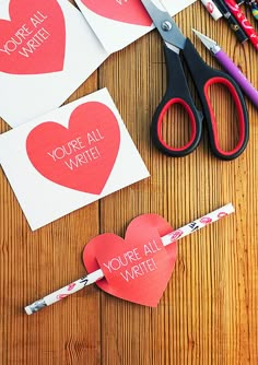 valentine's day crafts with paper hearts and scissors on a wooden table next to them