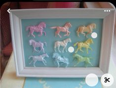 there are six plastic toy horses in a shadow box on the table next to each other