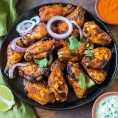 chicken wings with onions and cilantro on a black plate