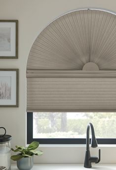 a kitchen window with an arched shade over the sink and faucet next to it