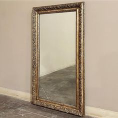 a large gold framed mirror sitting on top of a floor