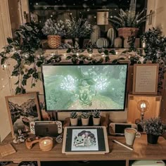 a computer desk with plants and pictures on it